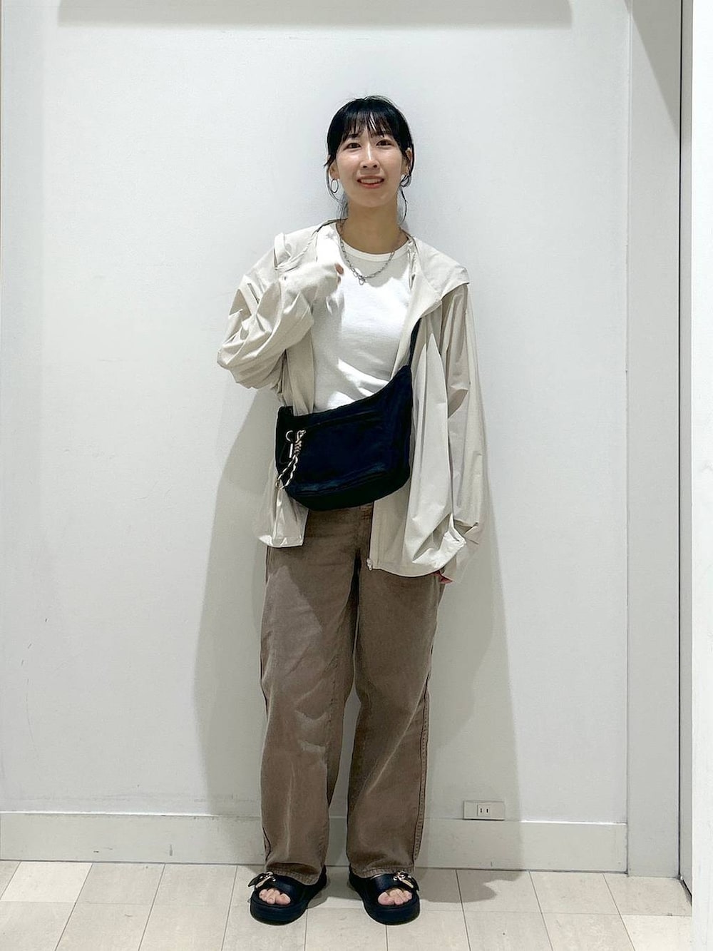 ブラック系のショルダーバッグ、ブラウン系のデニムパンツ、ベージュ系のマウンテンパーカーを着用したレディースの夏コーディネートの5枚目の写真