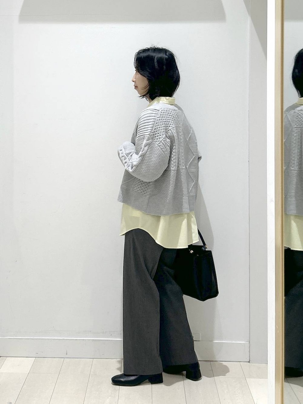 イエロー系のシャツ/ブラウス、グレー系のスラックス、ブラック系のブーツを着用したレディースの冬コーディネートの4枚目の写真
