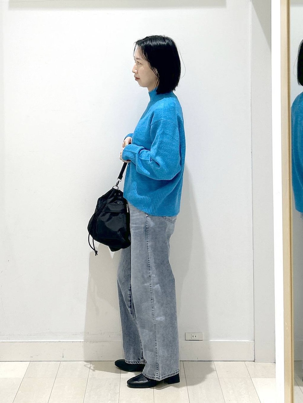 ブラック系のショルダーバッグ、ブルー系のデニムパンツ、ブラック系のブーツを着用したレディースの冬コーディネートの4枚目の写真