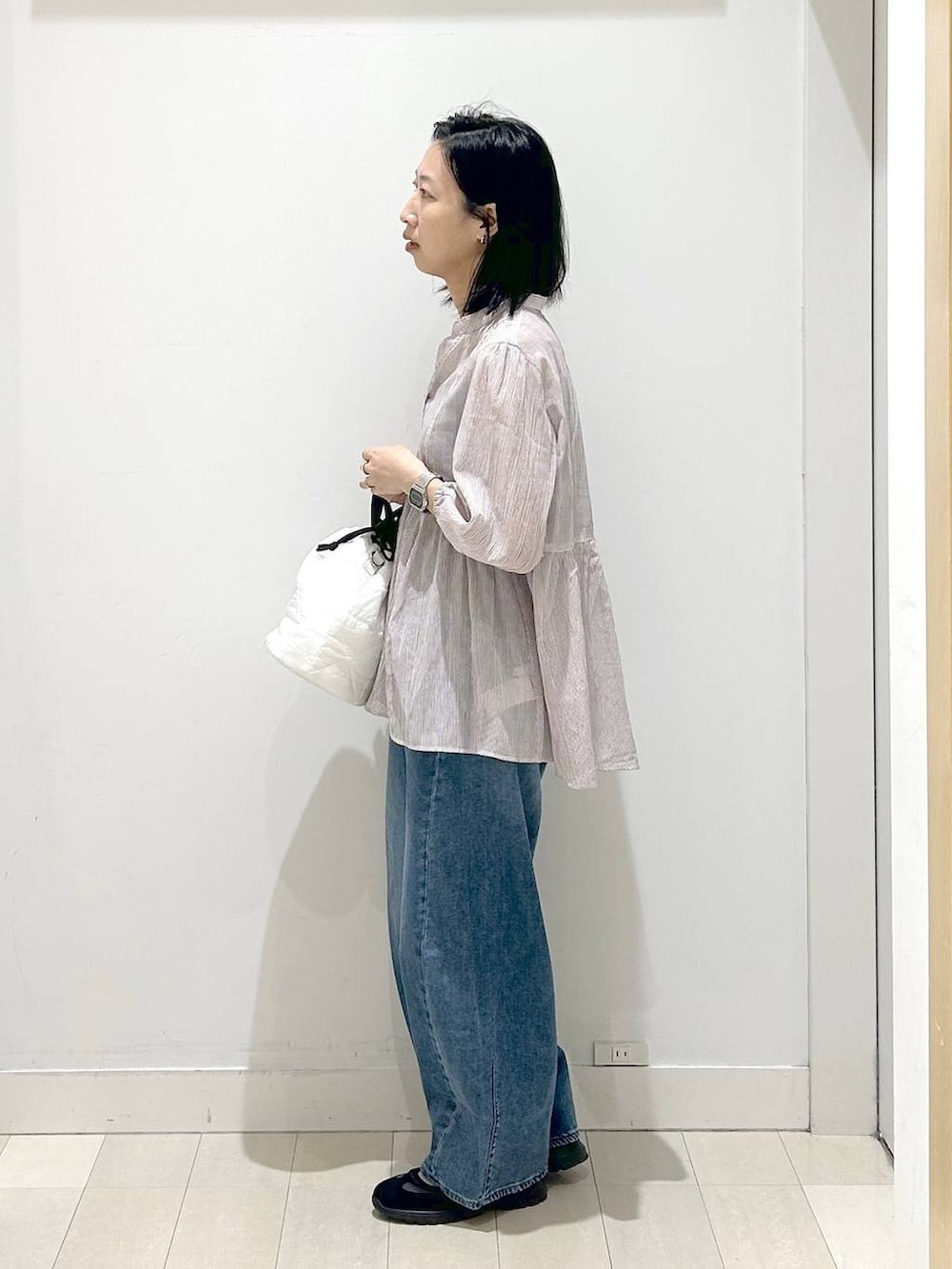 ホワイト系のハンドバッグ、ブルー系のデニムパンツ、レッド系のシャツ/ブラウスを着用したレディースの春コーディネートの2枚目の写真