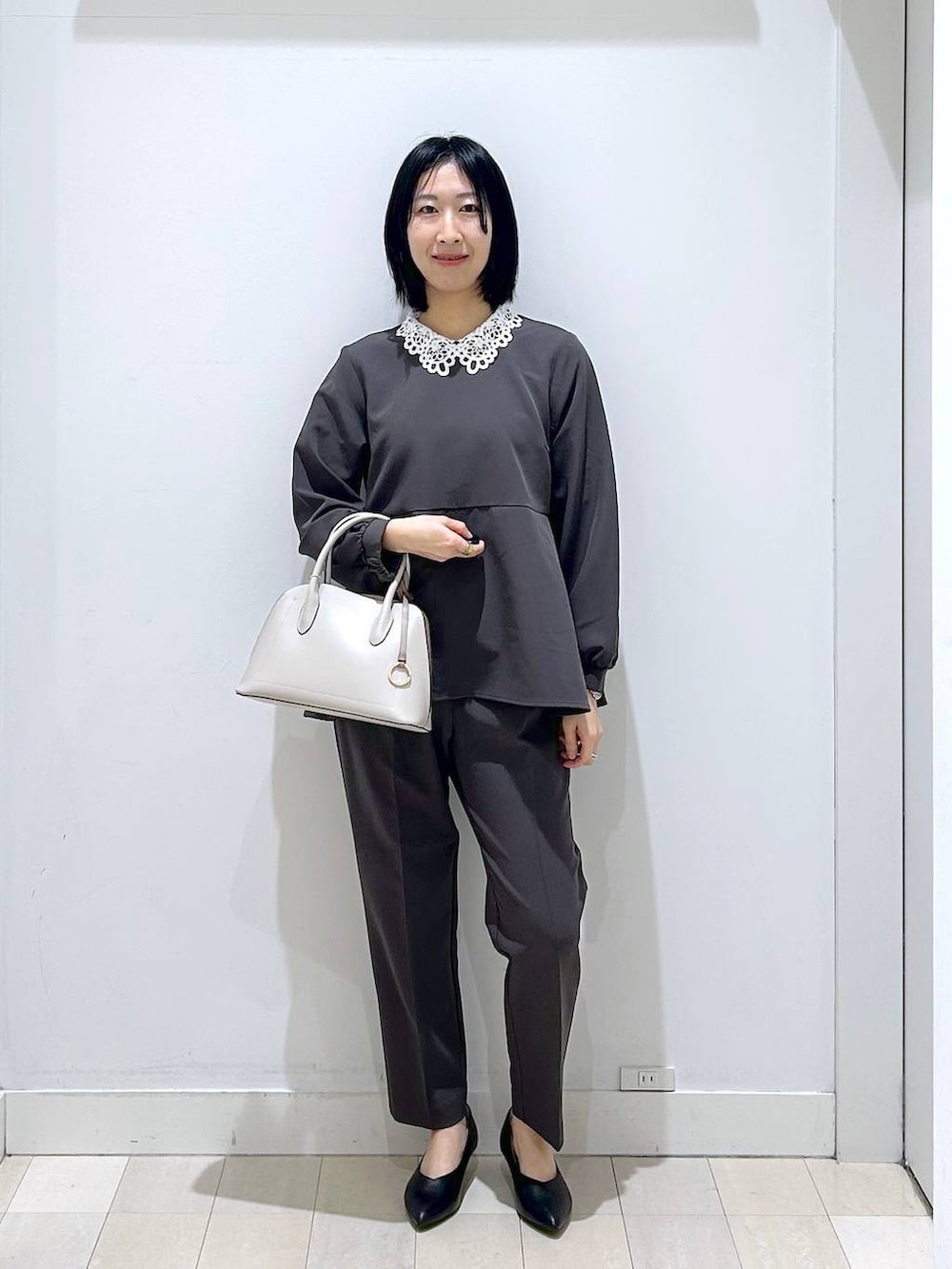 ホワイト系のショルダーバッグ、グレー系のセットアップ、ブラック系のパンプスを着用したレディースの冬コーディネートの5枚目の写真