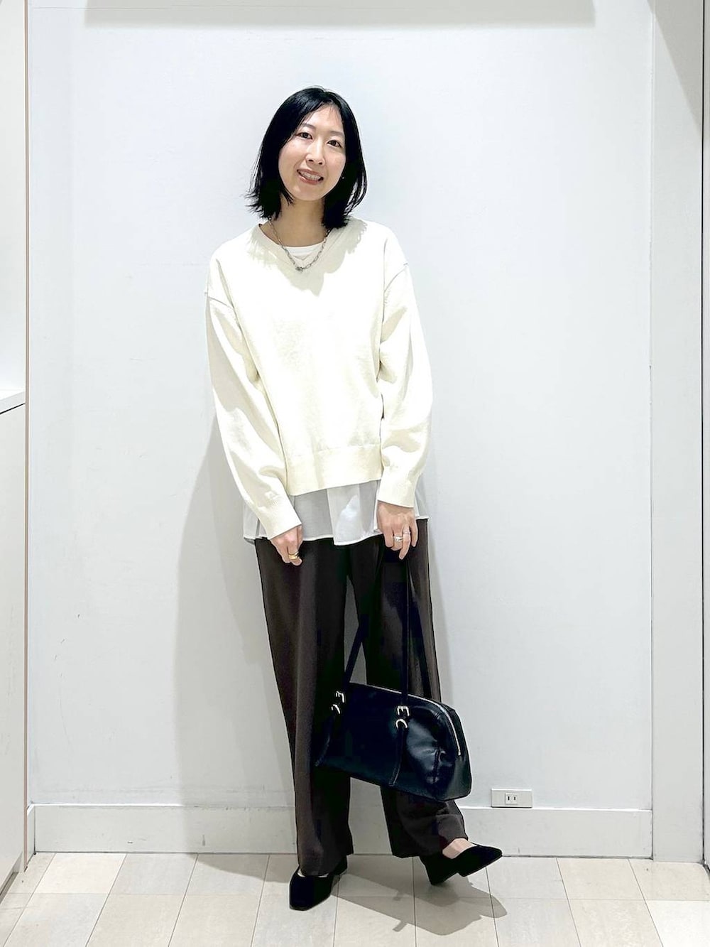 ベージュ系のニット/セーター、ブラウン系のその他パンツ、ホワイト系のタンクトップを着用したレディースの春コーディネートの5枚目の写真