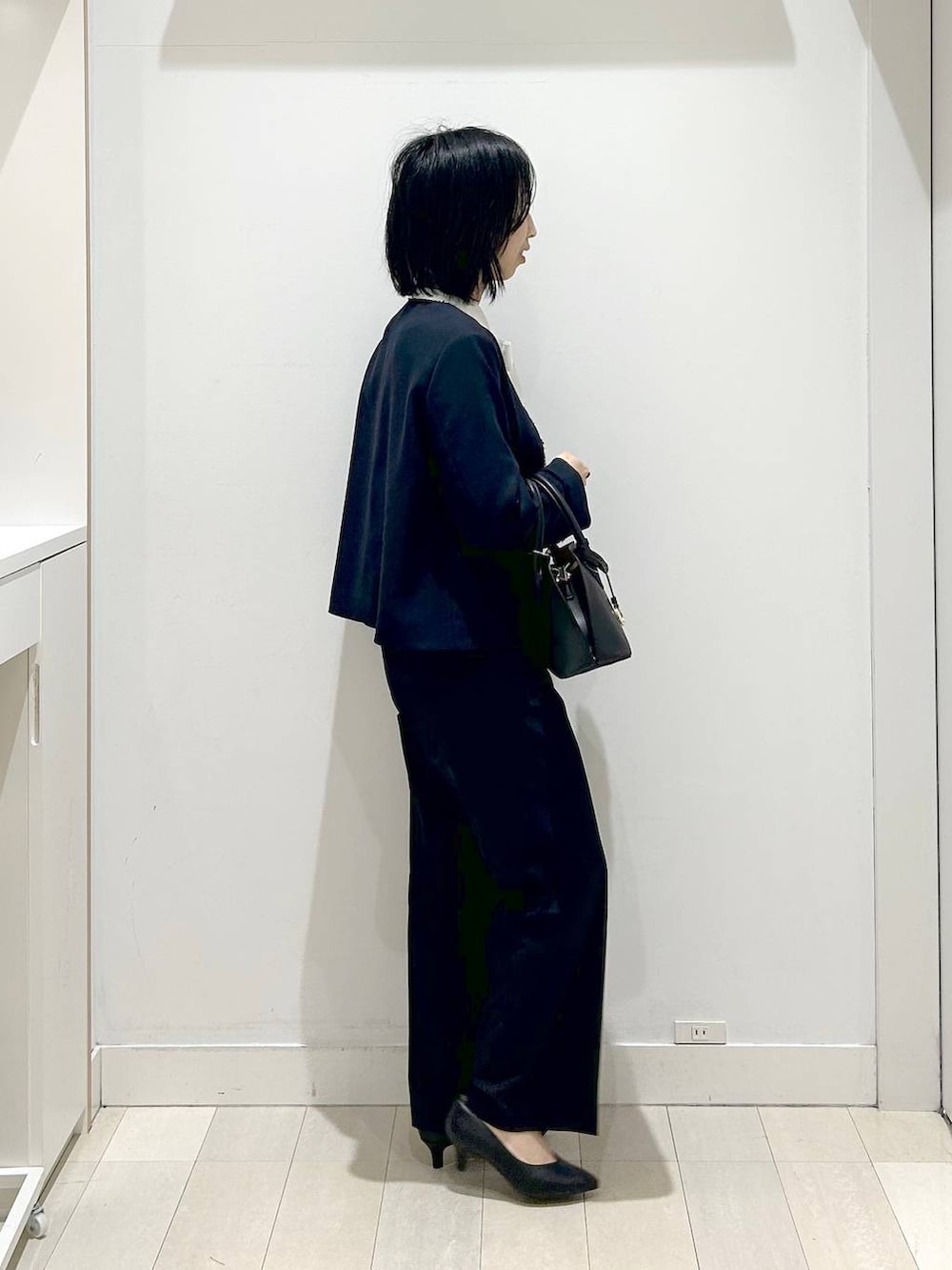 ホワイト系のショルダーバッグ、ブラック系のパンプス、ブルー系のスラックスを着用したレディースの冬コーディネートの4枚目の写真