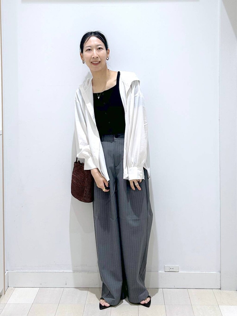 グレー系のその他パンツ、ホワイト系のTシャツ/カットソー、ブラウン系のクラッチバッグを着用したレディースの夏コーディネートの5枚目の写真