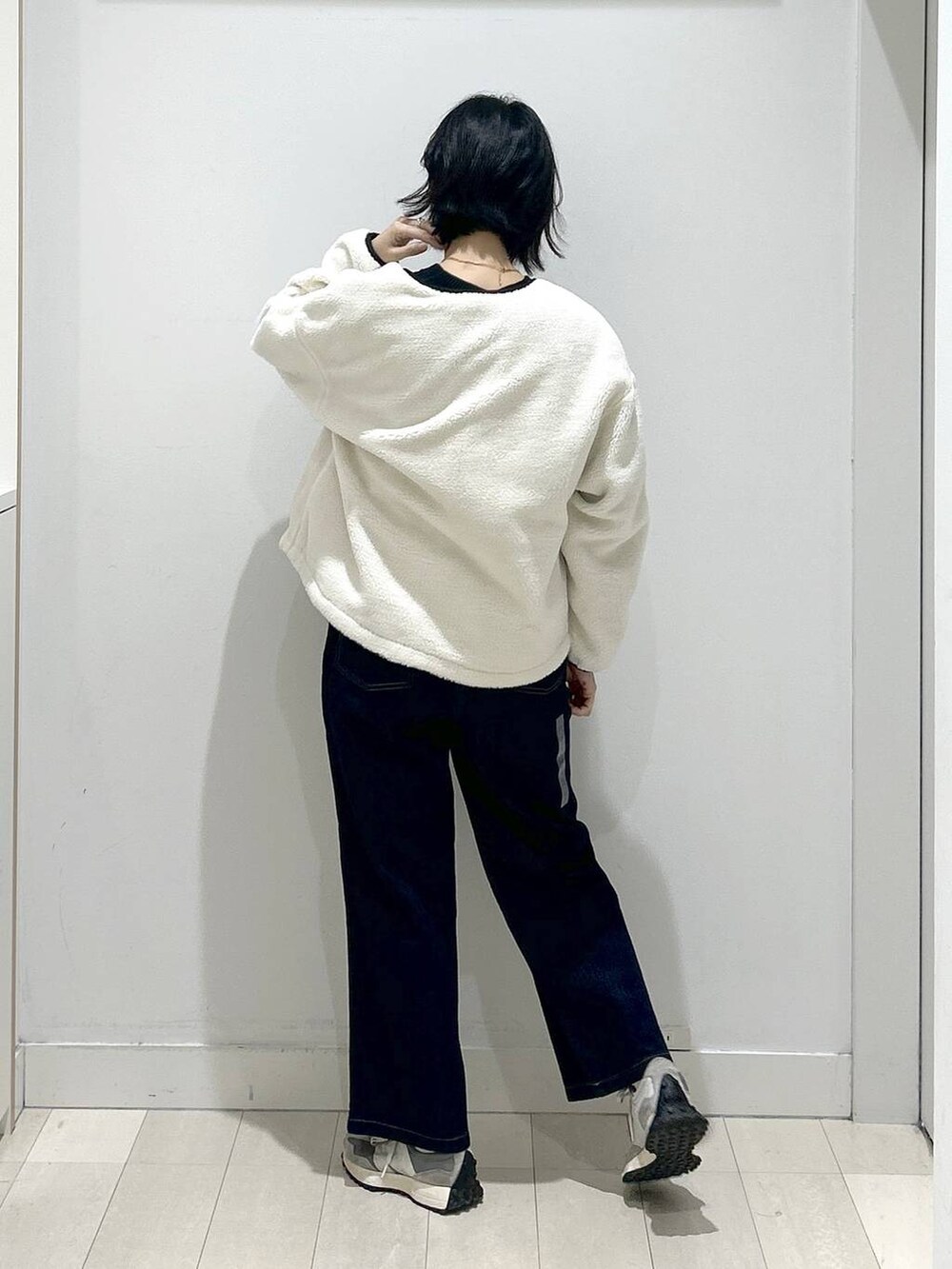 ブラック系のニット/セーター、ホワイト系のブルゾン、ブルー系のデニムパンツを着用したレディースの秋コーディネートの3枚目の写真