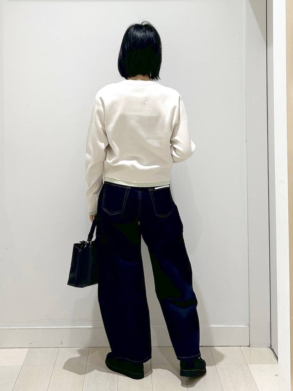 ブラック系のローファー、ブラック系のショルダーバッグ、ブルー系のデニムパンツを着用したレディースの冬コーディネートの3枚目の写真