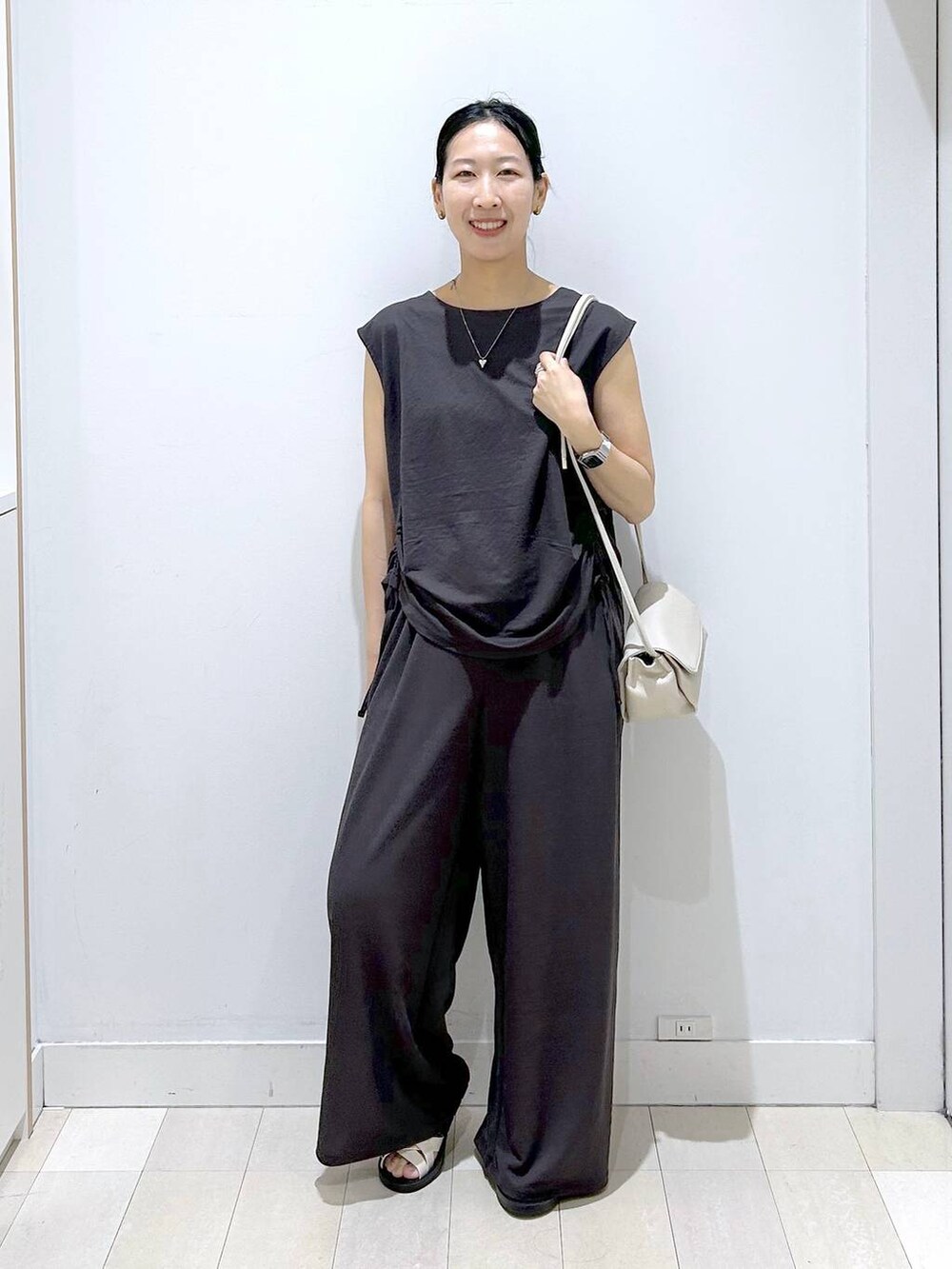 ベージュ系のショルダーバッグ、ブラック系のTシャツ/カットソー、ベージュ系のサンダルを着用したレディースの夏コーディネートの5枚目の写真