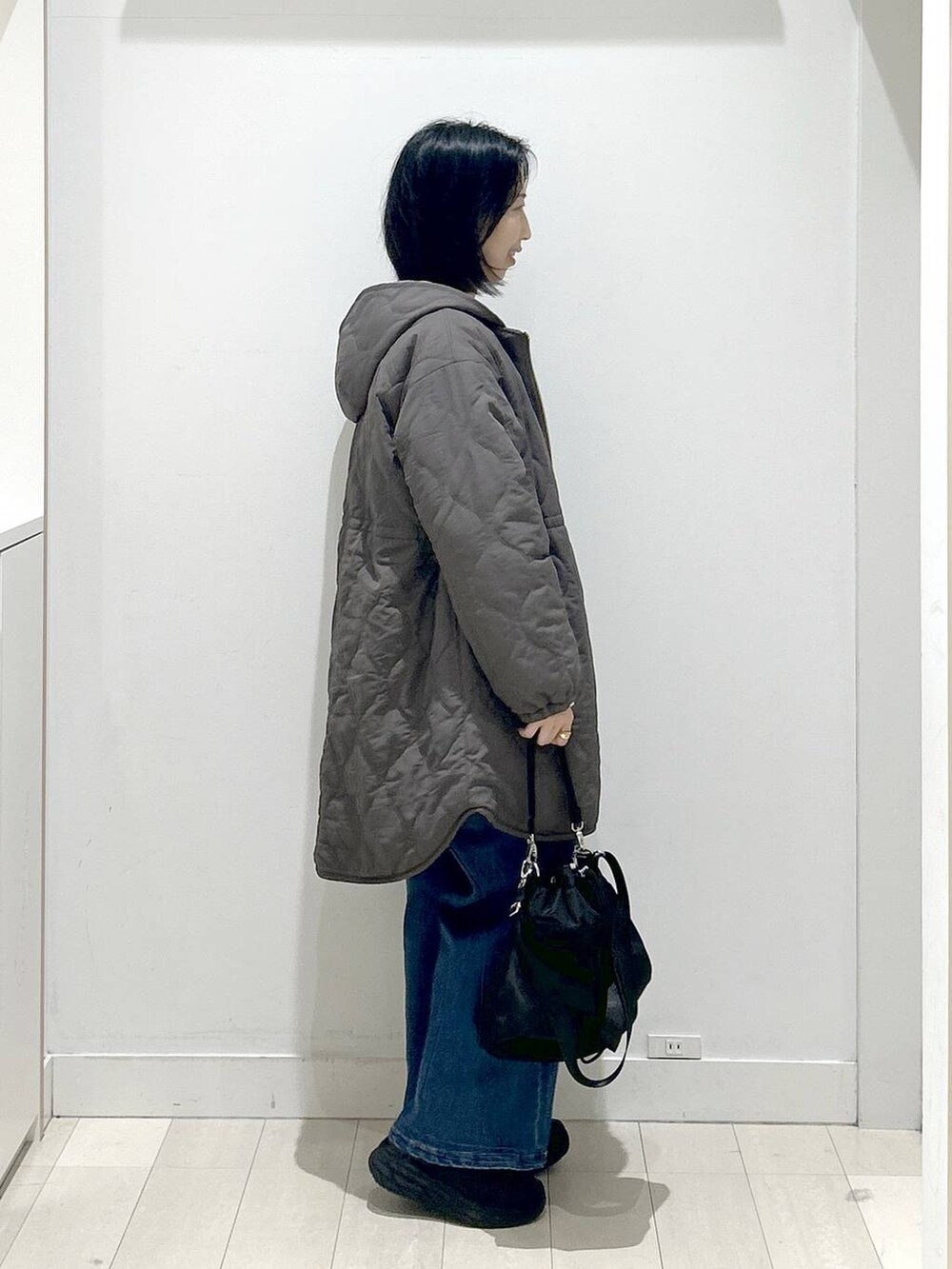 ブラック系のショルダーバッグ、ブラウン系のブルゾン、ホワイト系のTシャツ/カットソーを着用したレディースの冬コーディネートの2枚目の写真