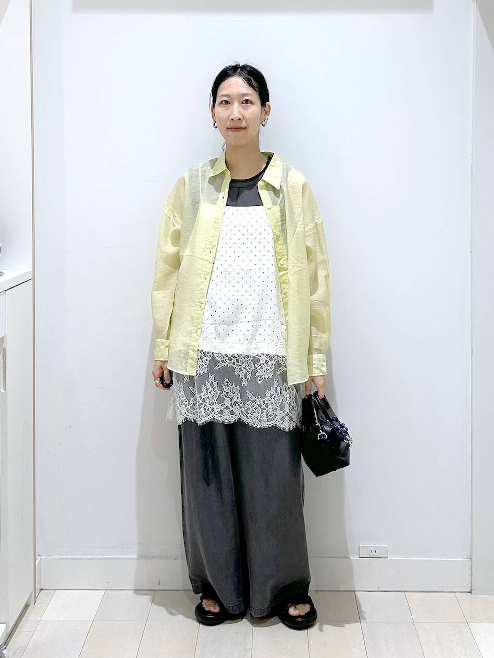 イエロー系のシャツ/ブラウス、ホワイト系のキャミソール、ブラック系のデニムパンツを着用したレディースの春コーディネートの5枚目の写真