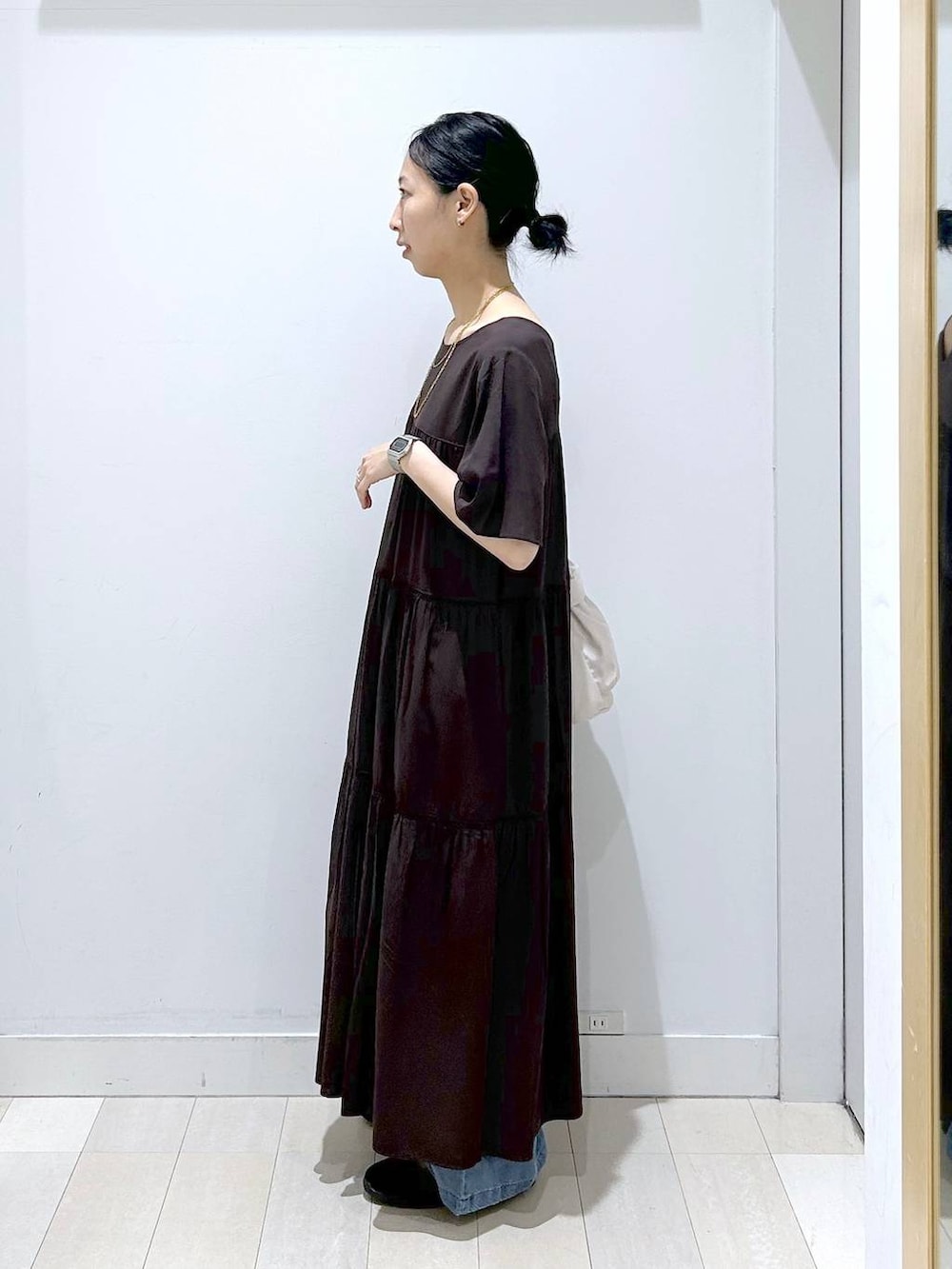 ホワイト系のショルダーバッグ、ブラウン系のワンピース、ブルー系のデニムパンツを着用したレディースの春コーディネートの2枚目の写真