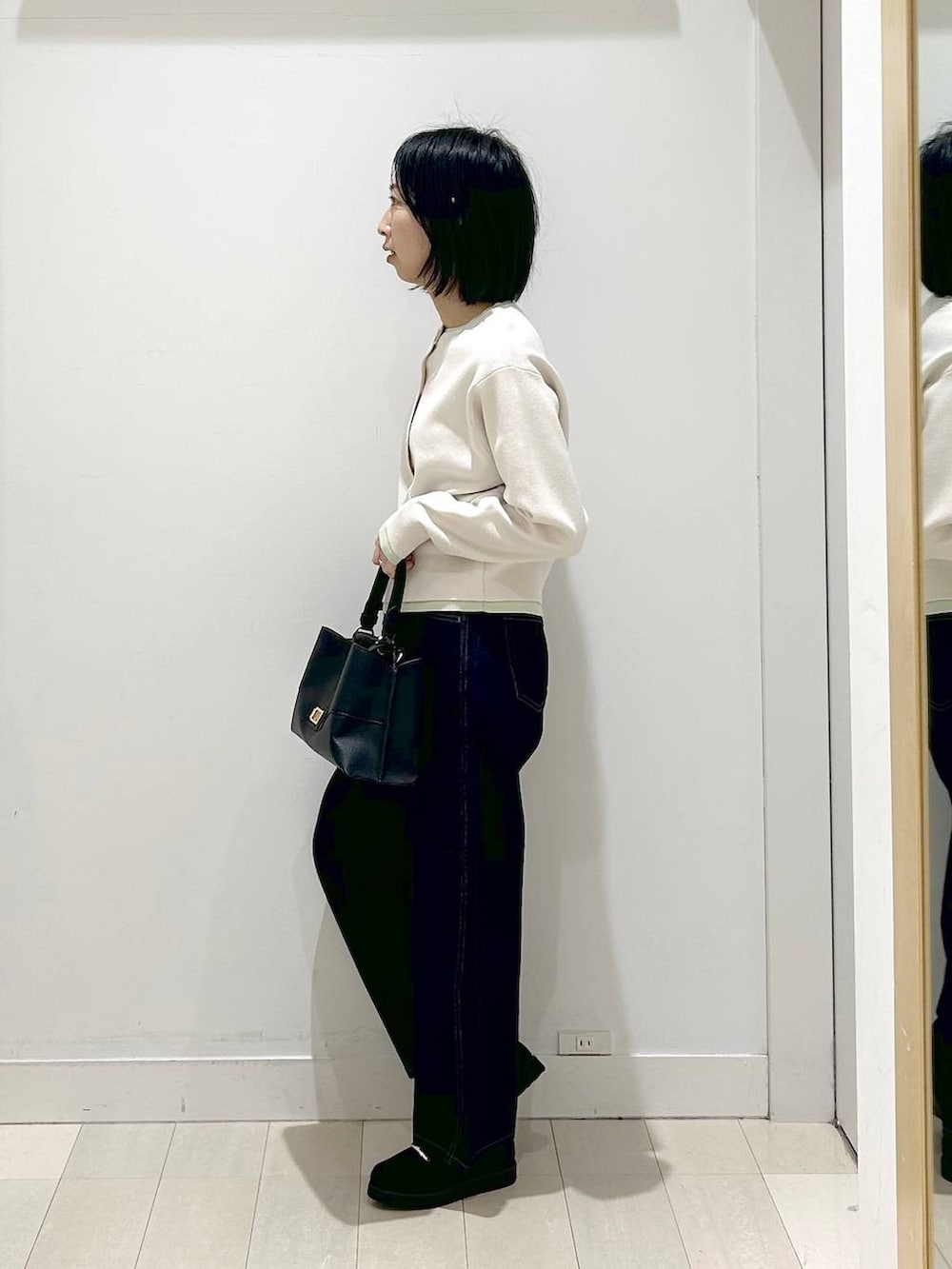 ブラック系のローファー、ブラック系のショルダーバッグ、ブルー系のデニムパンツを着用したレディースの冬コーディネートの2枚目の写真