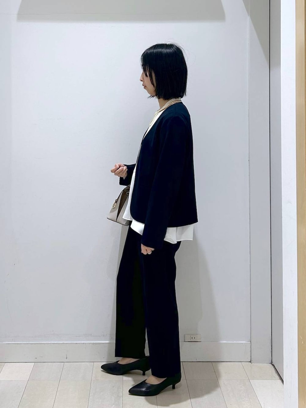 ホワイト系のショルダーバッグ、ブルー系のセットアップ、ブラック系のパンプスを着用したレディースの冬コーディネートの4枚目の写真