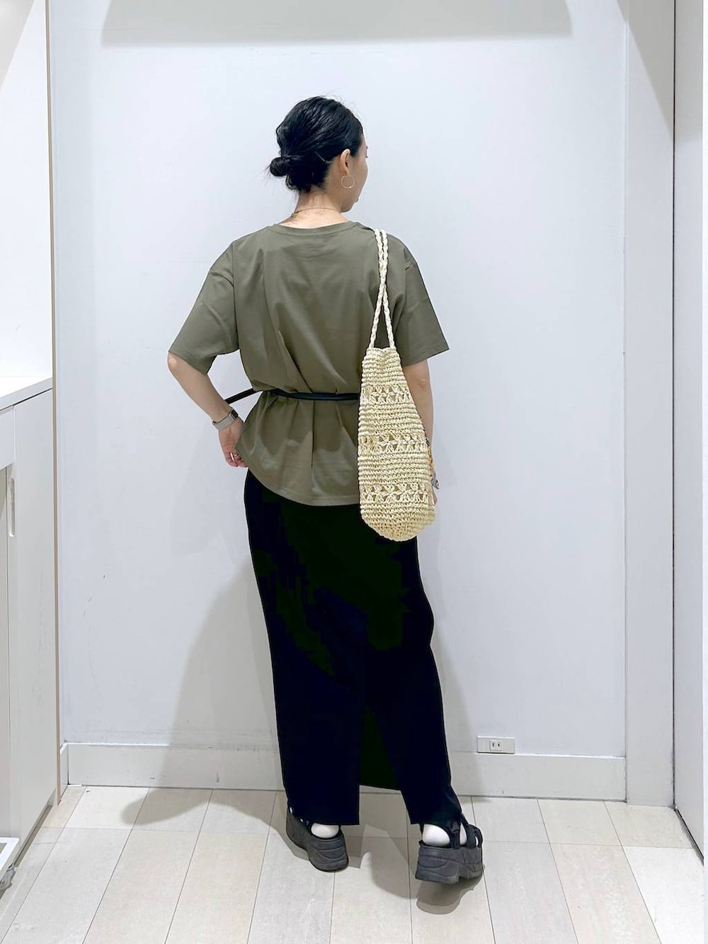 グリーン系のTシャツ/カットソー、ベージュ系のトートバッグ、ブラック系のスカートを着用したレディースの夏コーディネートの3枚目の写真
