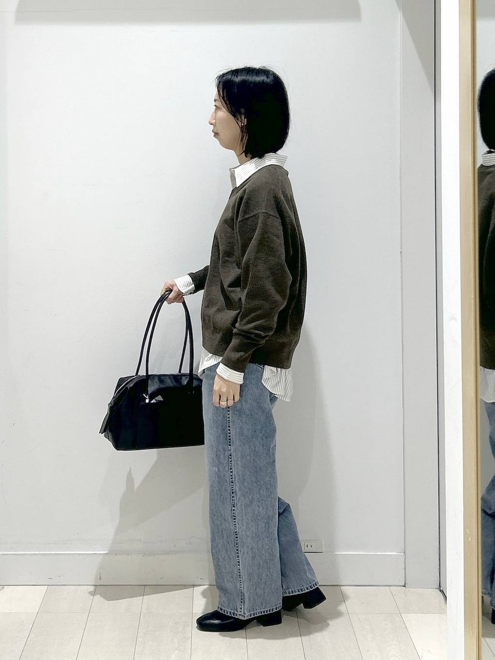 ブラック系のボストンバッグ、ブルー系のデニムパンツ、その他のシャツ/ブラウスを着用したレディースの冬コーディネートの4枚目の写真