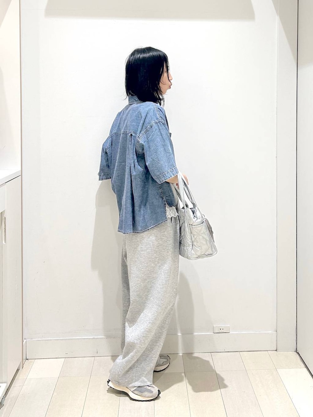 シルバー系のトートバッグ、ホワイト系のTシャツ/カットソー、ブルー系のシャツ/ブラウスを着用したレディースの春コーディネートの4枚目の写真