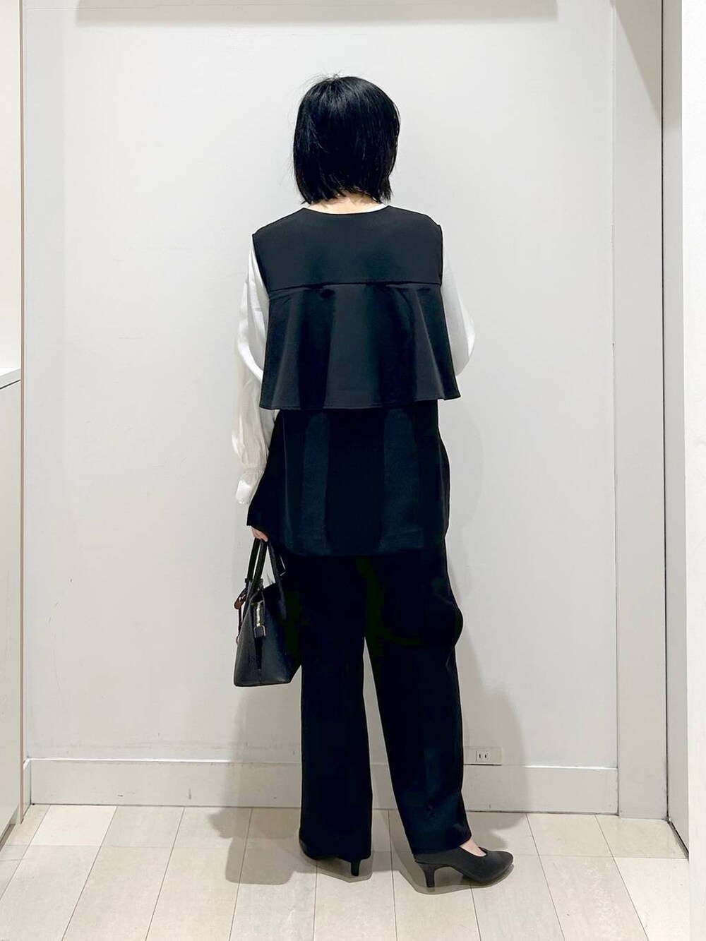 ブラック系のショルダーバッグ、ブラック系のパンプス、ブラック系のセットアップを着用したレディースの冬コーディネートの3枚目の写真