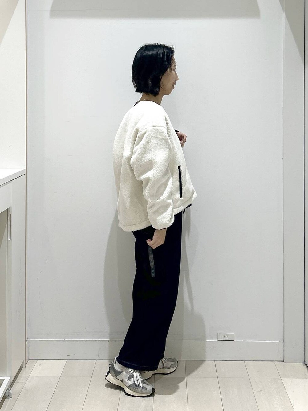 ブラック系のニット/セーター、ホワイト系のブルゾン、ブルー系のデニムパンツを着用したレディースの秋コーディネートの2枚目の写真