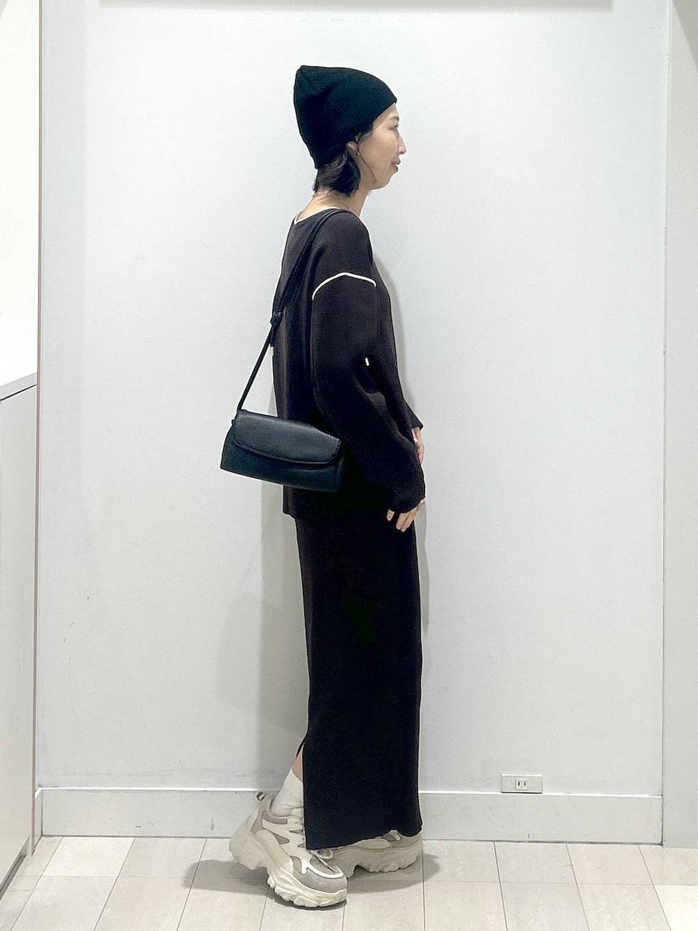 ブラック系のショルダーバッグ、ブラウン系のワンピースを着用したレディースの冬コーディネートの2枚目の写真