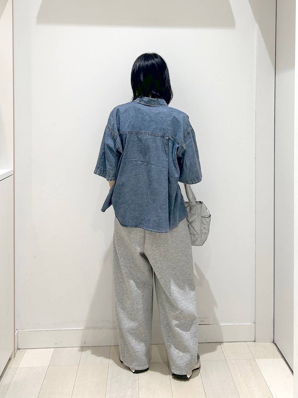 シルバー系のトートバッグ、ホワイト系のTシャツ/カットソー、ブルー系のシャツ/ブラウスを着用したレディースの春コーディネートの3枚目の写真