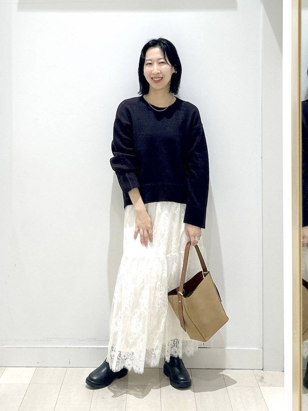 ブラウン系のショルダーバッグ、ブラック系のブーツ、ブラウン系のワンピースを着用したレディースの冬コーディネートの5枚目の写真