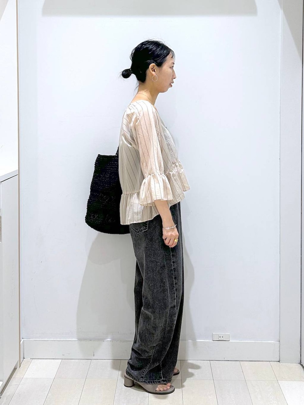 ブラック系のデニムパンツ、ブラック系のトートバッグ、ベージュ系のカーディガン/ボレロを着用したレディースの夏コーディネートの4枚目の写真