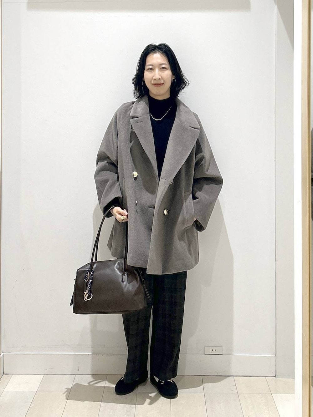 ブラウン系のボストンバッグ、ブラウン系のチェスターコート、ブラック系のその他パンツを着用したレディースの冬コーディネートの5枚目の写真