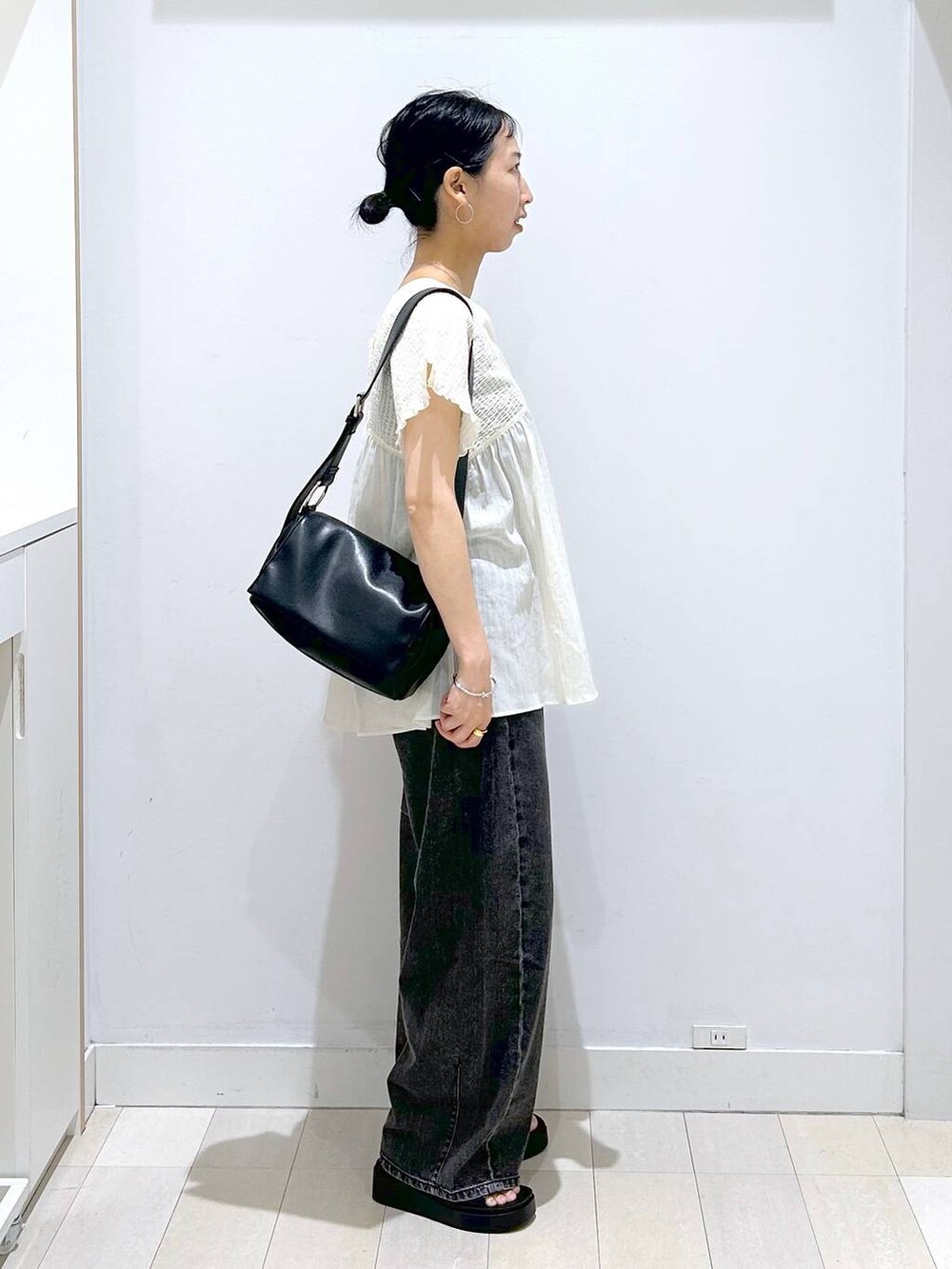 ブラック系のデニムパンツ、ベージュ系のシャツ/ブラウス、ブラック系のサンダルを着用したレディースの夏コーディネートの4枚目の写真