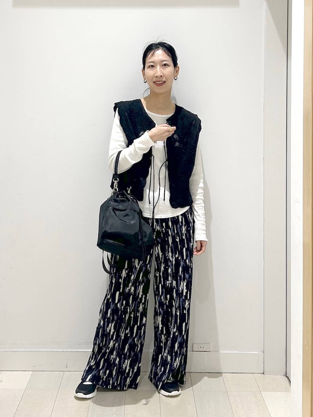 ブラック系のスニーカー、ブラック系のショルダーバッグ、ブルー系のその他パンツを着用したレディースの春コーディネートの5枚目の写真