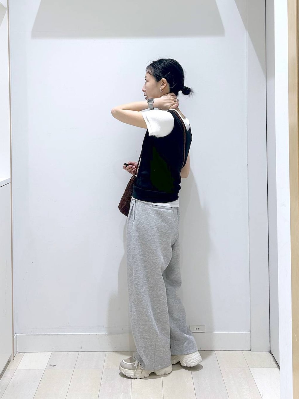 ブラック系のタンクトップ、ブラウン系のクラッチバッグ、グレー系のその他パンツを着用したレディースの春コーディネートの2枚目の写真