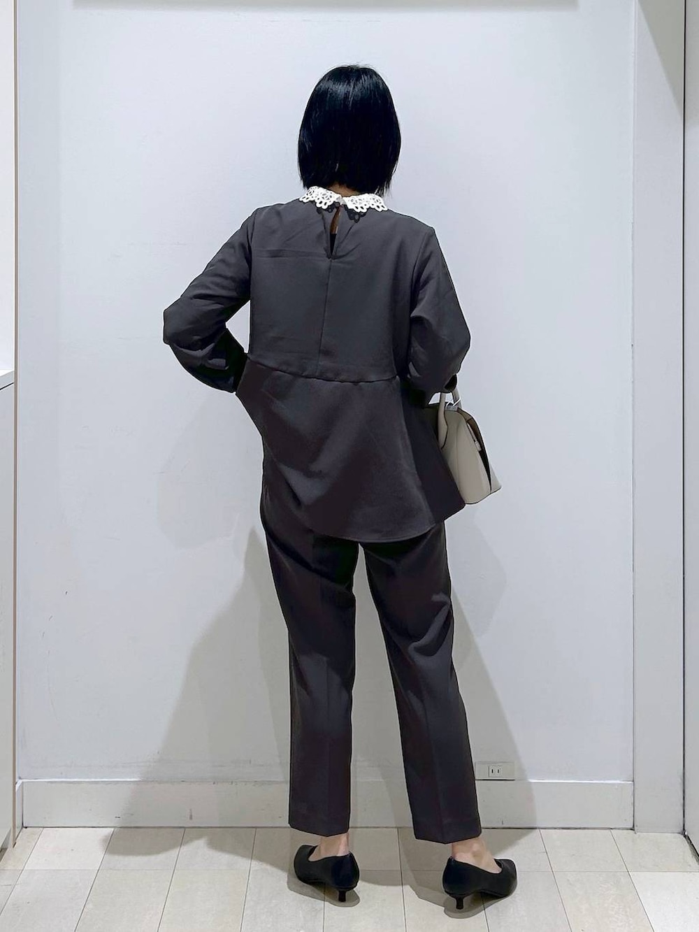 ホワイト系のショルダーバッグ、グレー系のセットアップ、ブラック系のパンプスを着用したレディースの冬コーディネートの3枚目の写真