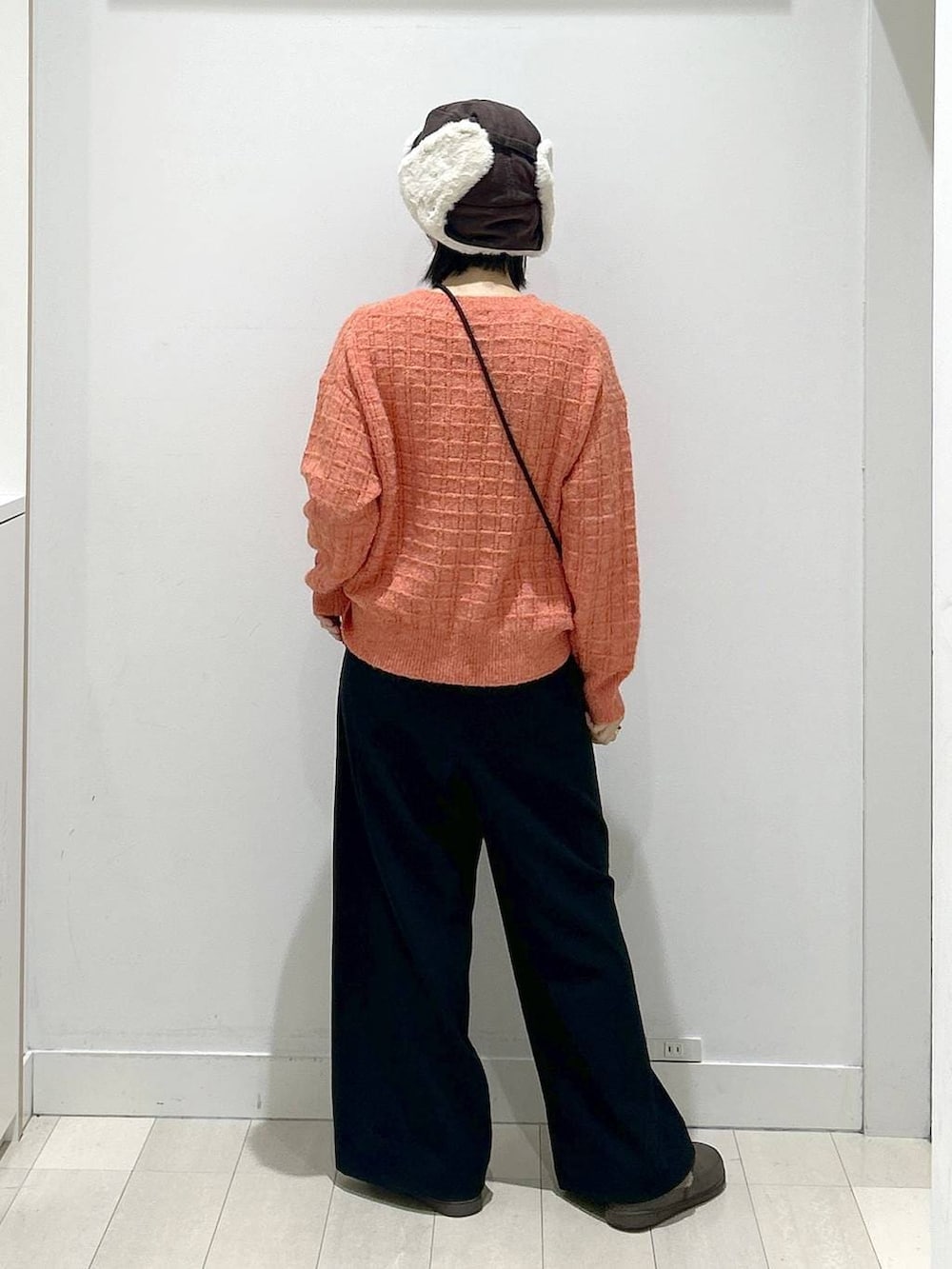 オレンジ系のニット/セーター、ブラック系のその他パンツ、グレー系のショルダーバッグを着用したレディースの冬コーディネートの3枚目の写真