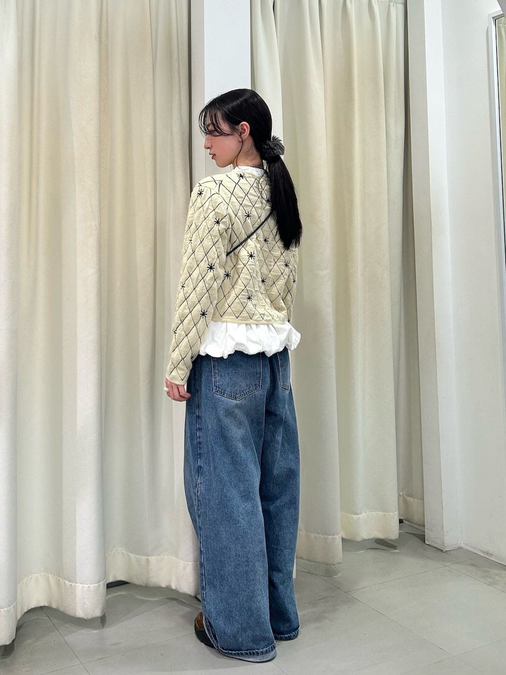 ベージュ系のニット/セーター、ホワイト系のTシャツ/カットソー、ブルー系のデニムパンツを着用したレディースの秋コーディネートの3枚目の写真