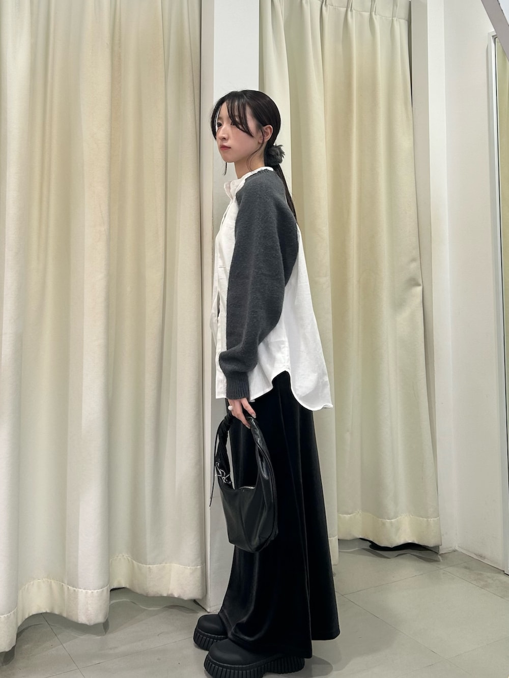 グレー系のシャツ/ブラウス、グレー系のスカート、ブラック系のハンドバッグを着用したレディースの秋コーディネートの2枚目の写真