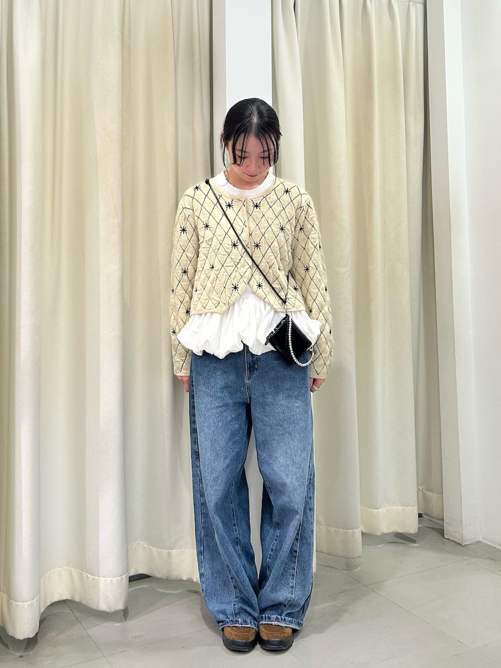 ベージュ系のニット/セーター、ホワイト系のTシャツ/カットソー、ブルー系のデニムパンツを着用したレディースの秋コーディネートの2枚目の写真