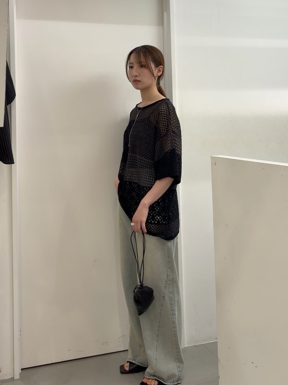 グレー系のニット/セーター、ブルー系のデニムパンツ、ブラック系のサンダルを着用したレディースの夏コーディネートの2枚目の写真