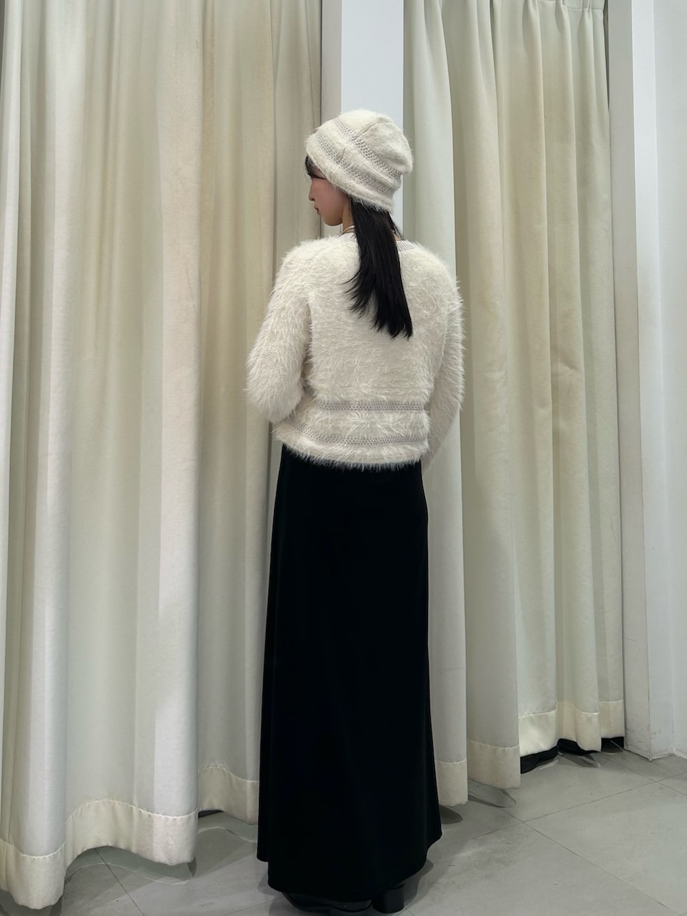 ホワイト系のニット/セーター、ブラック系のスカート、ブラック系のブーツを着用したレディースの秋コーディネートの3枚目の写真