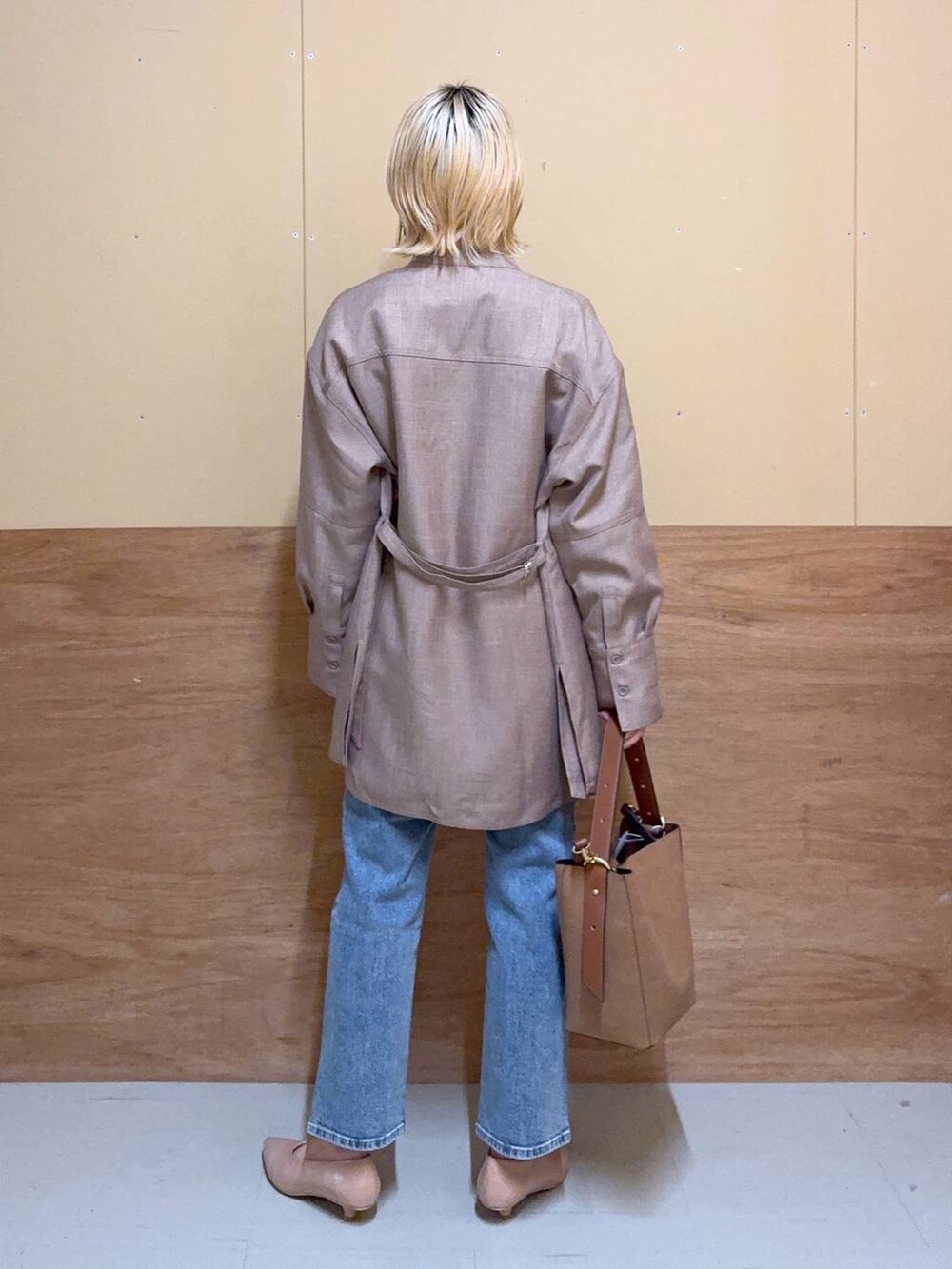 ブラウン系のショルダーバッグ、ベージュ系のパンプス、ブルー系のデニムパンツを着用したレディースの秋コーディネートの3枚目の写真