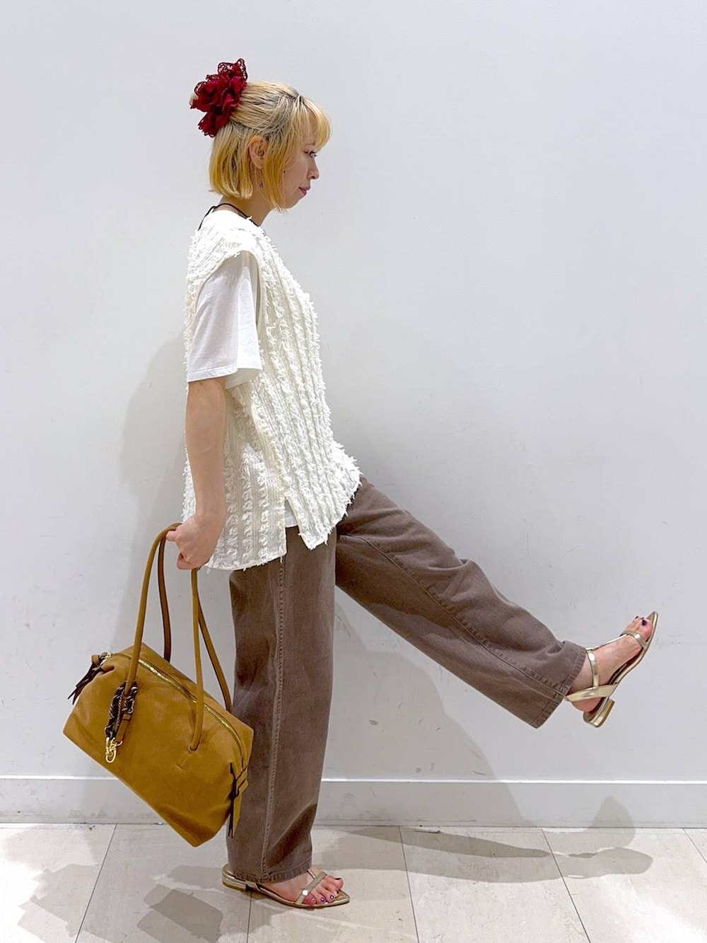 ゴールド系のサンダル、ブラウン系のデニムパンツ、ベージュ系のボストンバッグを着用したレディースの夏コーディネートの2枚目の写真