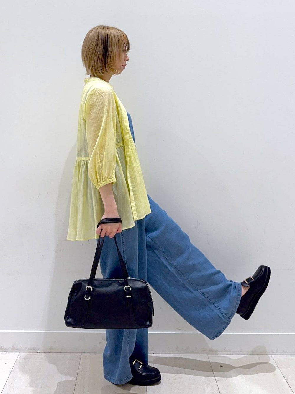 ブラック系のローファー、イエロー系のシャツ/ブラウス、ブラック系のショルダーバッグを着用したレディースの春コーディネートの2枚目の写真