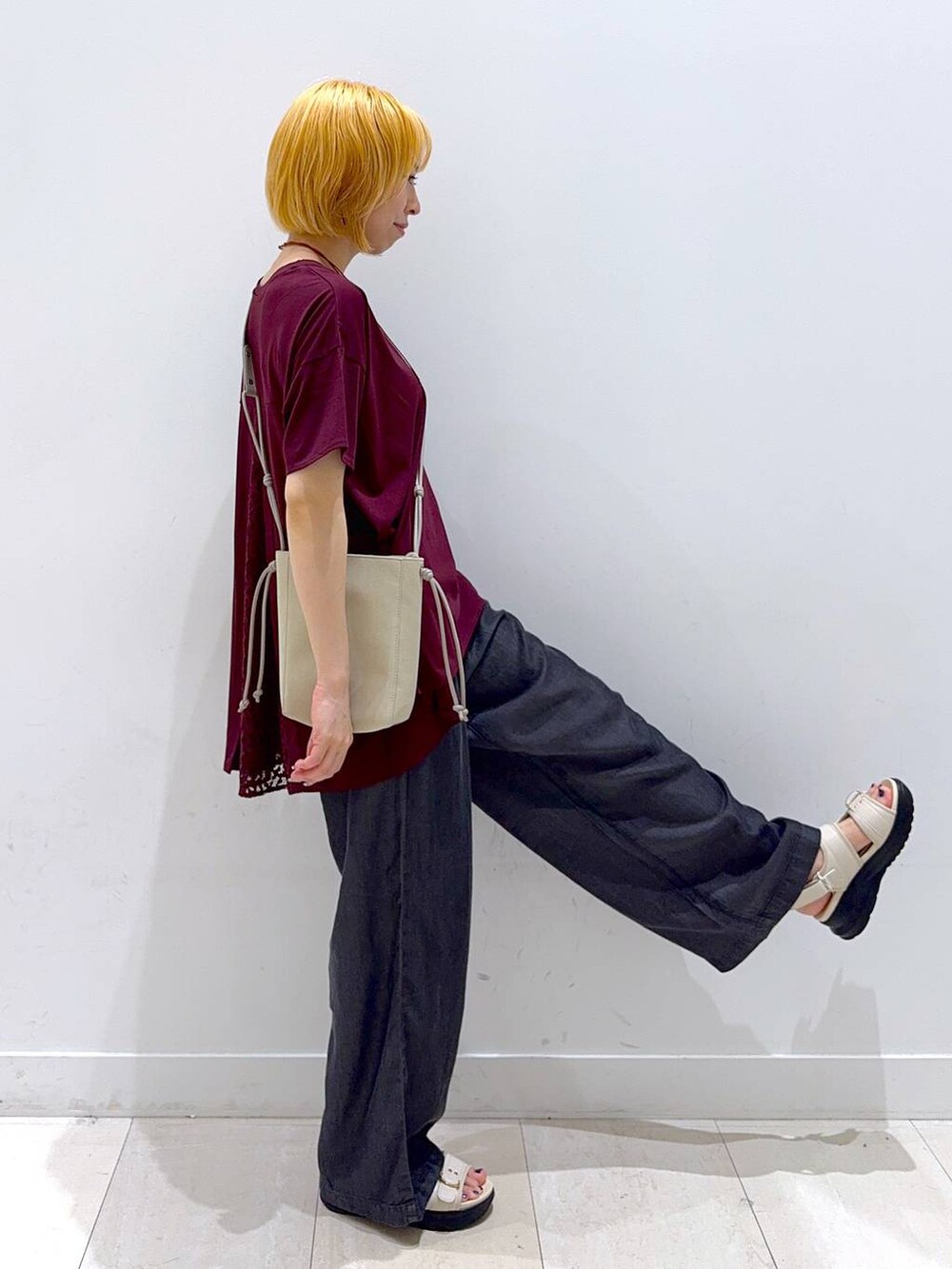 ベージュ系のショルダーバッグ、ホワイト系のサンダル、ブラック系のデニムパンツを着用したレディースの夏コーディネートの2枚目の写真