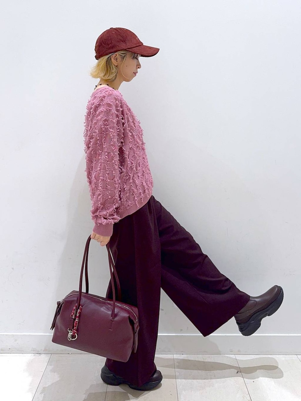 レッド系のボストンバッグ、レッド系のその他パンツ、ピンク系のカーディガン/ボレロを着用したレディースの秋コーディネートの2枚目の写真