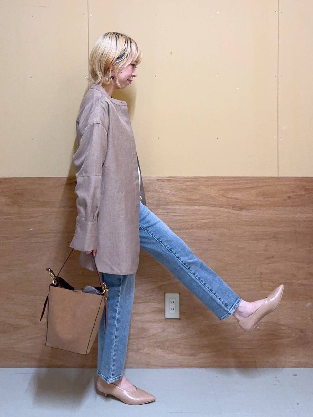 ブラウン系のショルダーバッグ、ベージュ系のパンプス、ブルー系のデニムパンツを着用したレディースの秋コーディネートの2枚目の写真