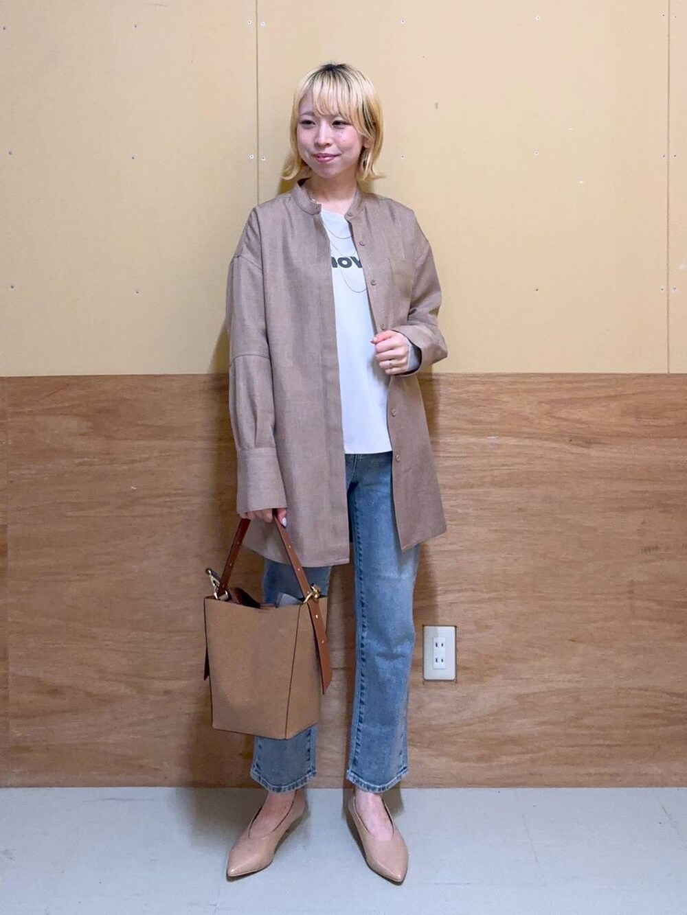 ブラウン系のショルダーバッグ、ベージュ系のパンプス、ブルー系のデニムパンツを着用したレディースの秋コーディネートの4枚目の写真