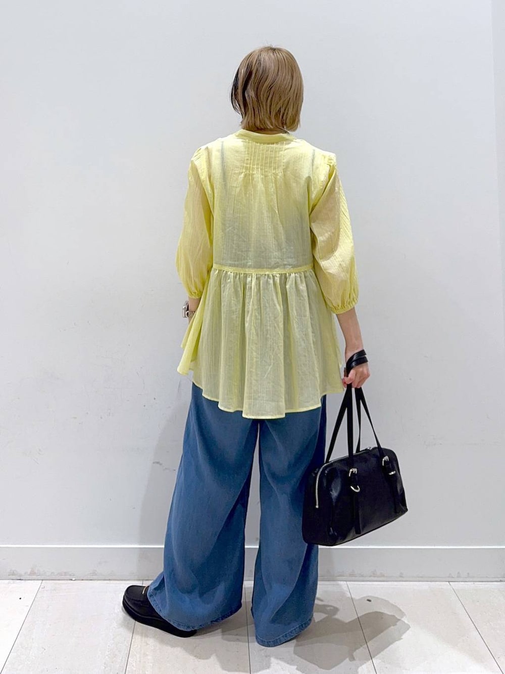 ブラック系のローファー、イエロー系のシャツ/ブラウス、ブラック系のショルダーバッグを着用したレディースの春コーディネートの3枚目の写真
