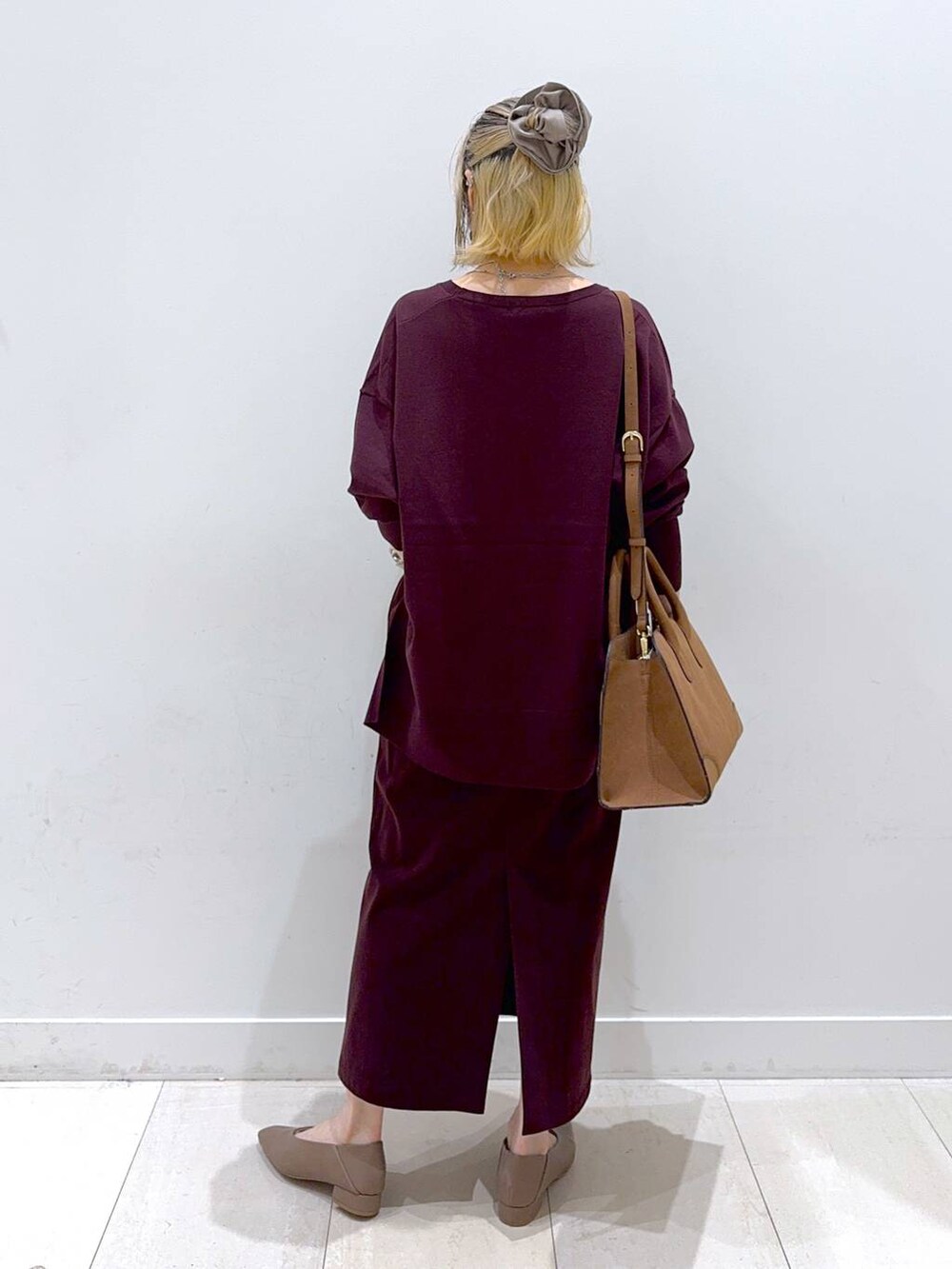 レッド系のニット/セーター、レッド系のスカート、ベージュ系のショルダーバッグを着用したレディースの秋コーディネートの3枚目の写真