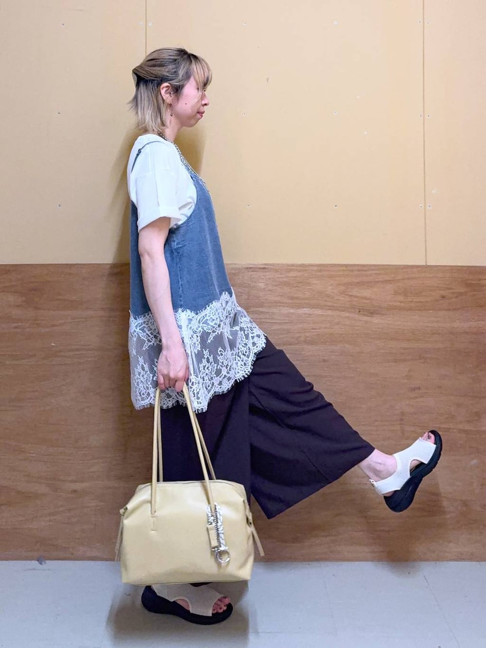 イエロー系のボストンバッグ、ブラウン系のその他パンツ、ホワイト系のTシャツ/カットソーを着用したレディースの春コーディネートの2枚目の写真