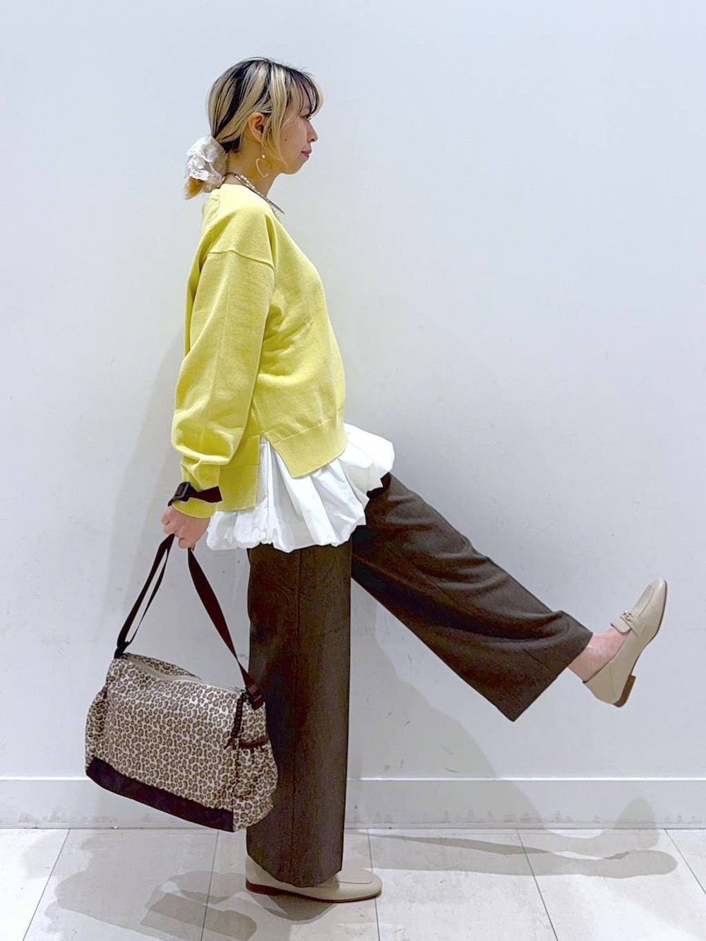 ブラウン系のその他パンツ、イエロー系のニット/セーター、ブラウン系のショルダーバッグを着用したレディースの春コーディネートの2枚目の写真