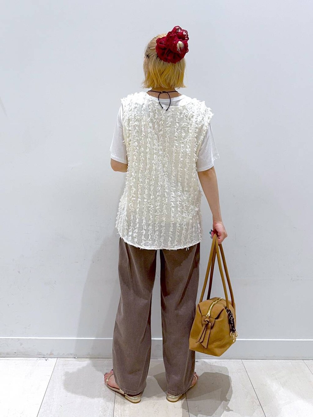 ゴールド系のサンダル、ブラウン系のデニムパンツ、ベージュ系のボストンバッグを着用したレディースの夏コーディネートの3枚目の写真