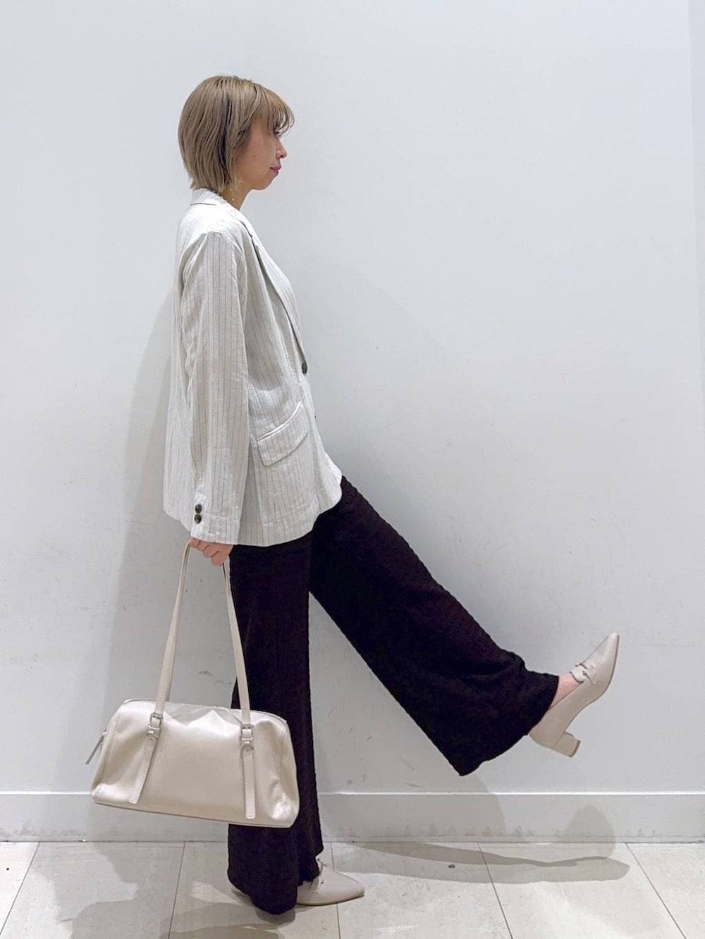 グレー系のテーラードジャケット、ホワイト系のローファー、ベージュ系のショルダーバッグを着用したレディースの春コーディネートの2枚目の写真