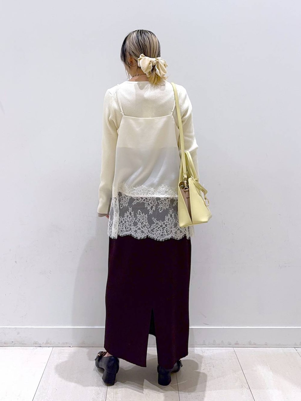 ブラック系のローファー、イエロー系のショルダーバッグ、ホワイト系のニット/セーターを着用したレディースの冬コーディネートの3枚目の写真